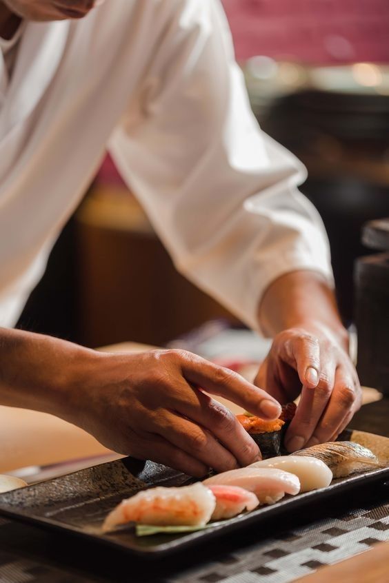 Les mains d'Hiroshi disposent les nigiri